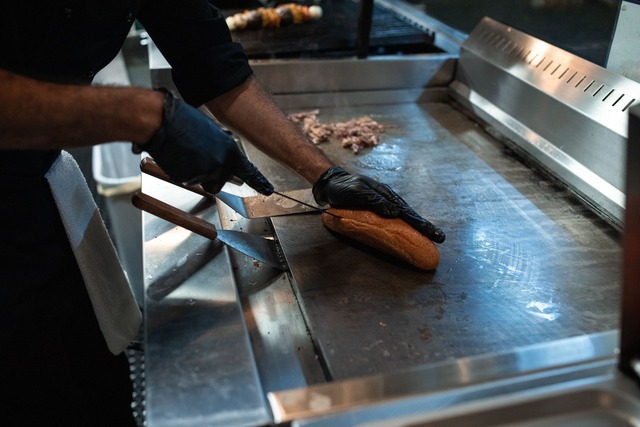 Cuisinier préparant un burger sur une plancha professionnelle