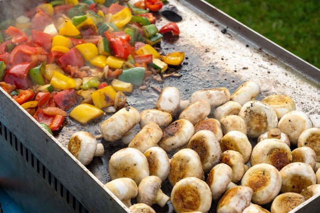 Légumes et champignons en cuisson sur une plancha
